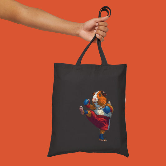 Black tote bag with a Muay thai guinea pig hamster design held by a hand 